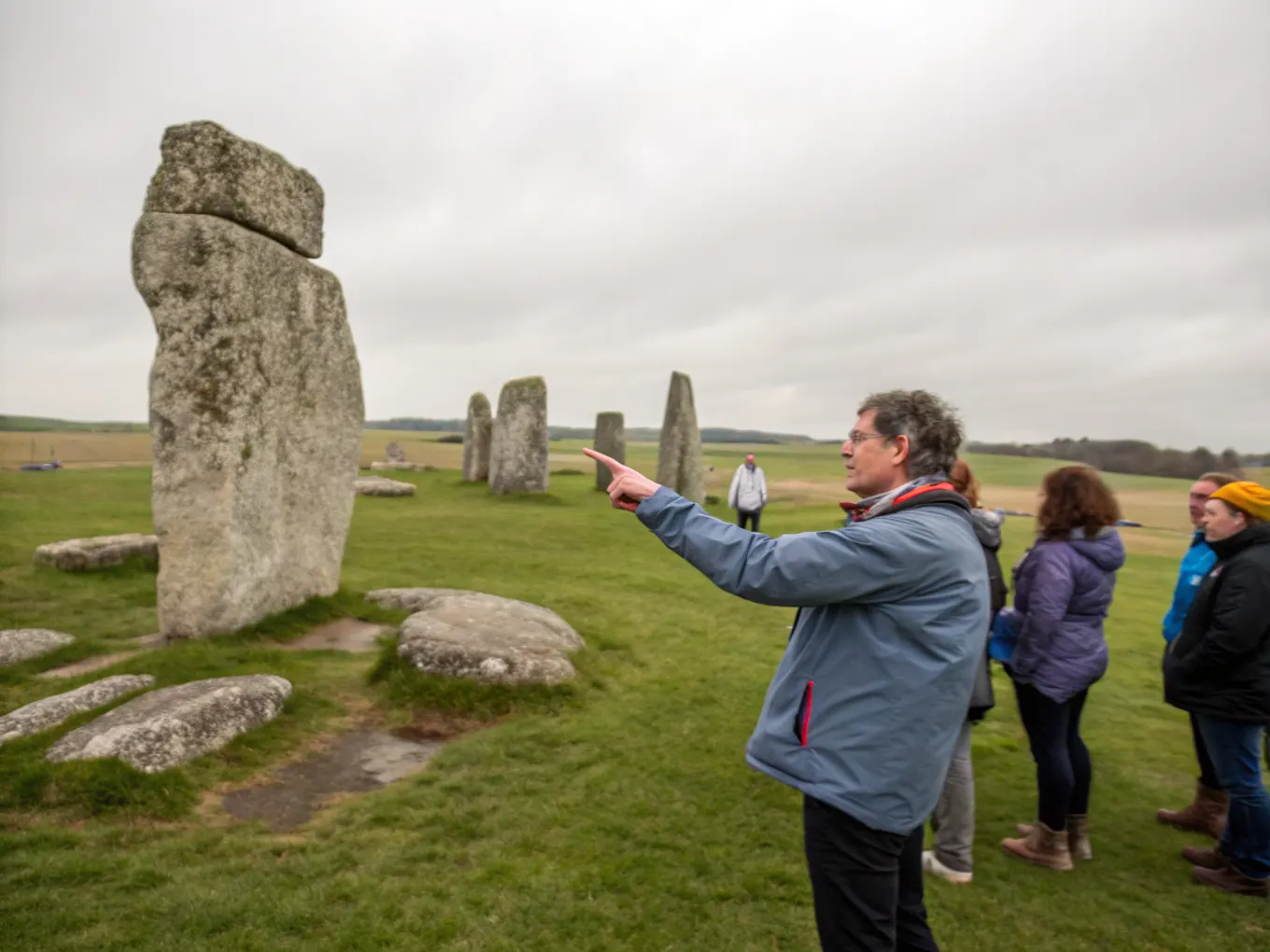 A tour guide leading a small group among ancient standing stones near Salisbury